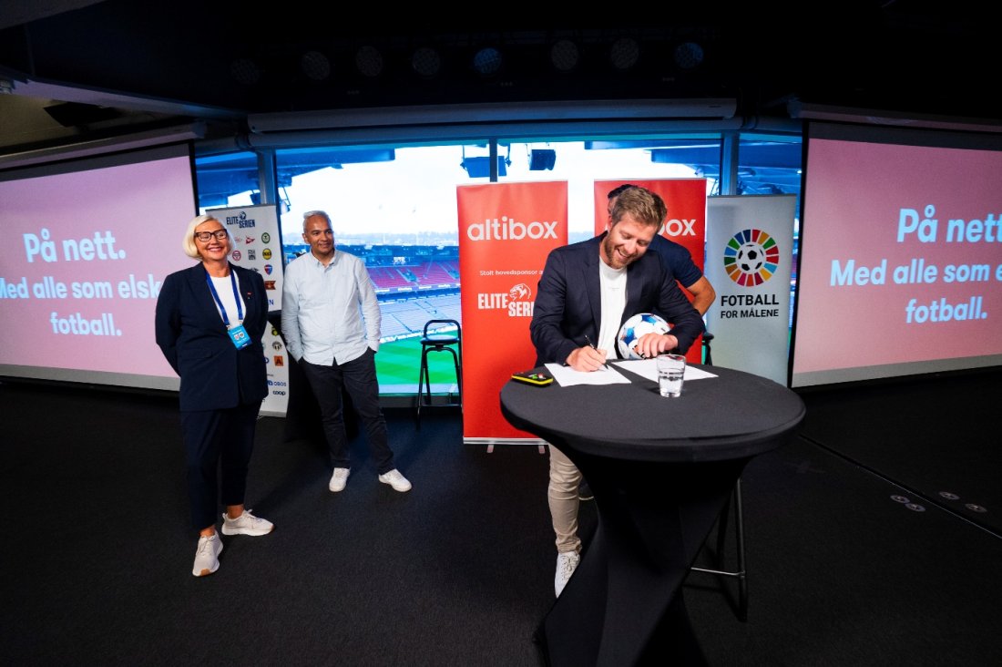 Jens Haugland, adm. dir. i Norsk Toppfotball signerer ny avtale med Altibox. I bakgrunnen står Vibecke Utengen og Shiraz Abid og følger med. 